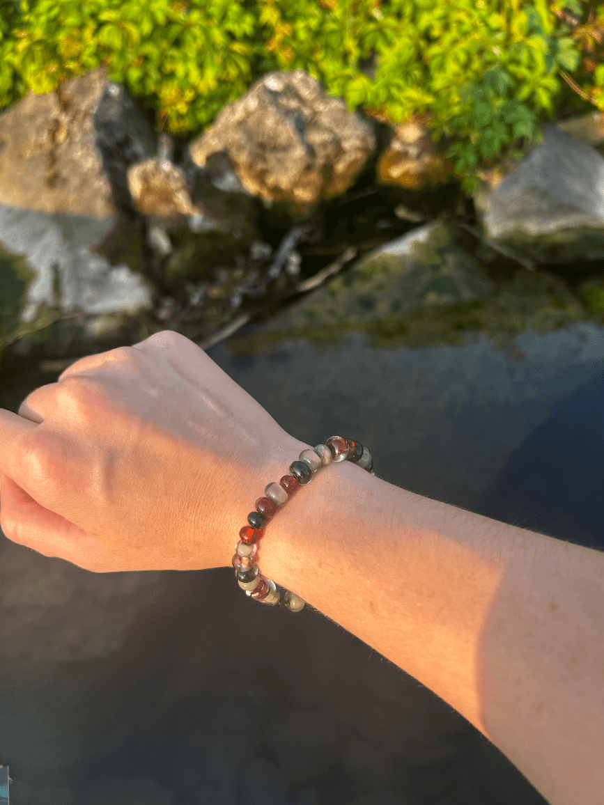 Bracelet artisanal en perles de verre teintes ambre et gris taupe porté au poignet