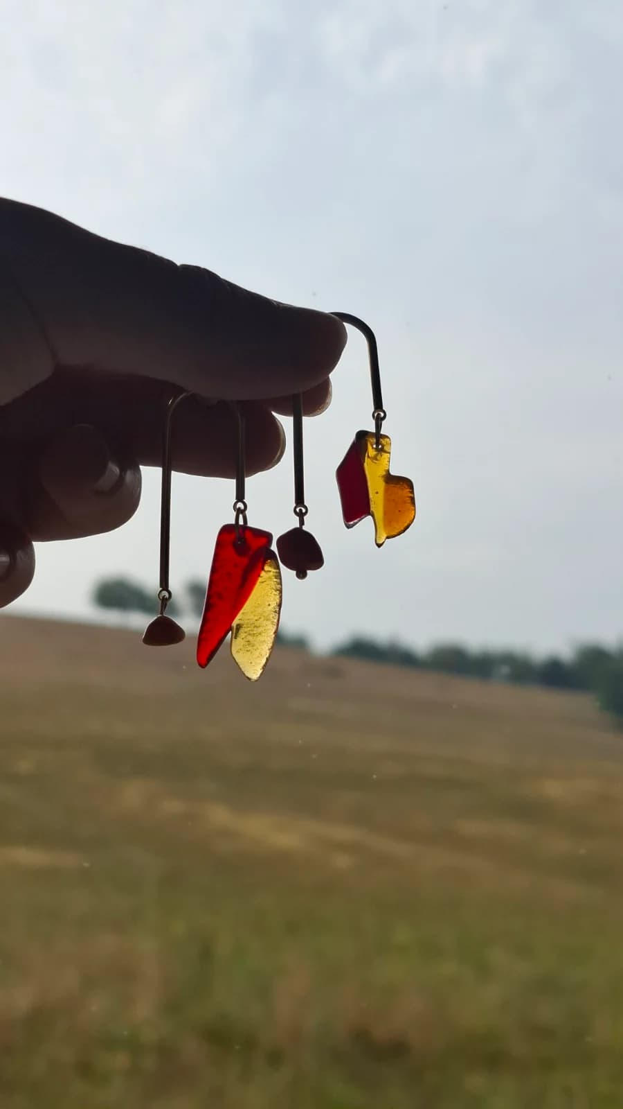 Paire de boucles d'oreilles graphiques en verre rouge et ambré tenue en contre-jour