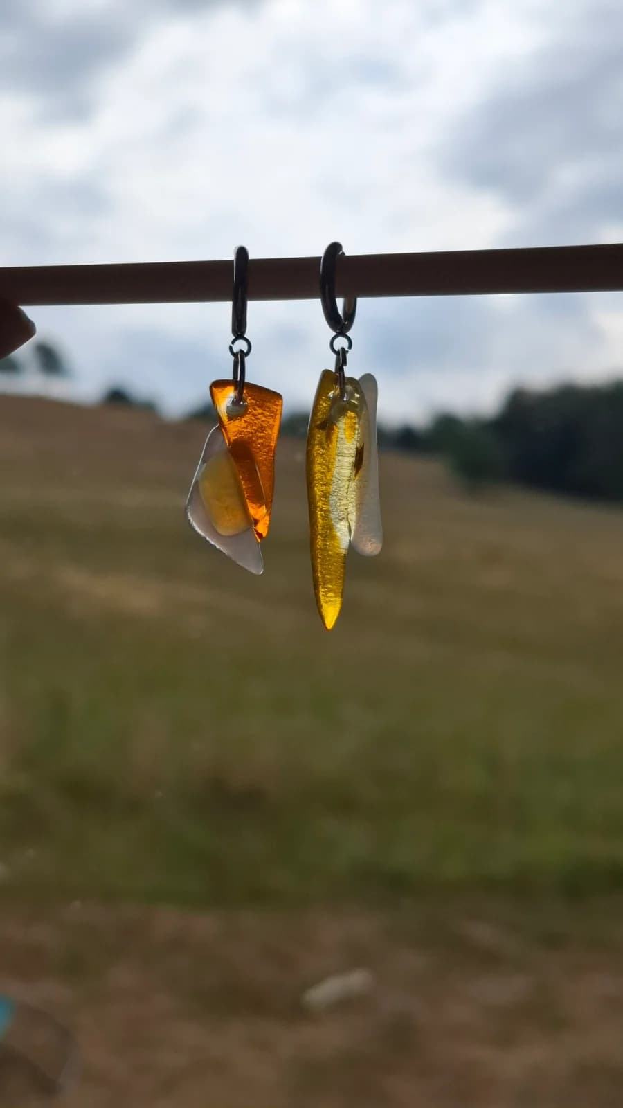 Boucles d'oreilles en verre translucide jaune et orangé présentées à la lumière naturelle en extérieur