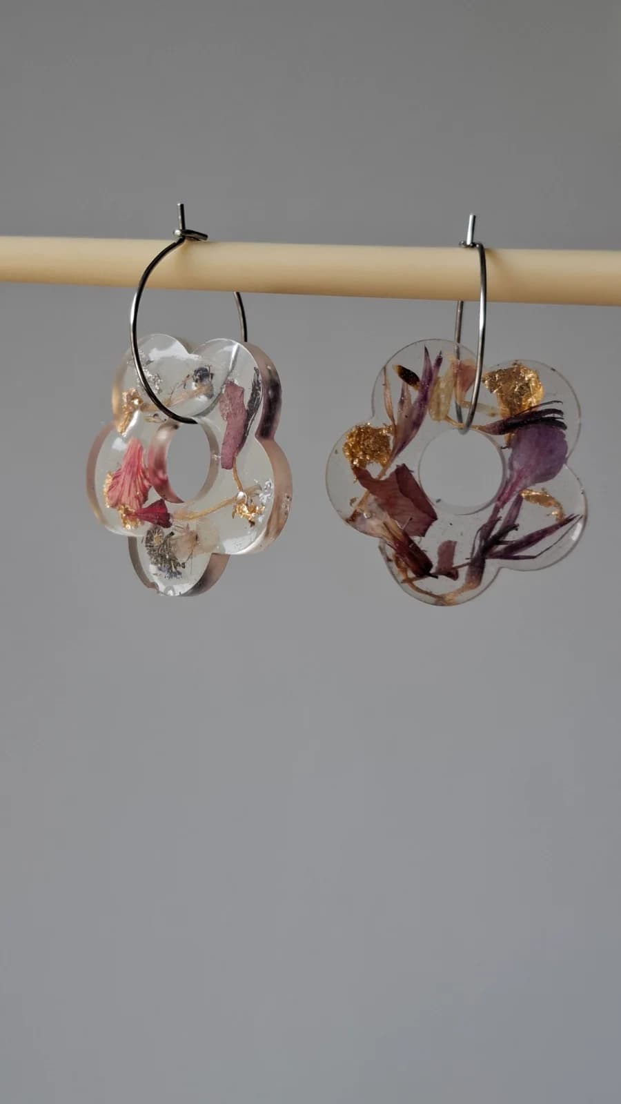 Boucles d'oreilles créoles suspendues avec pendentifs floraux en résine et inclusions de pétales colorés.