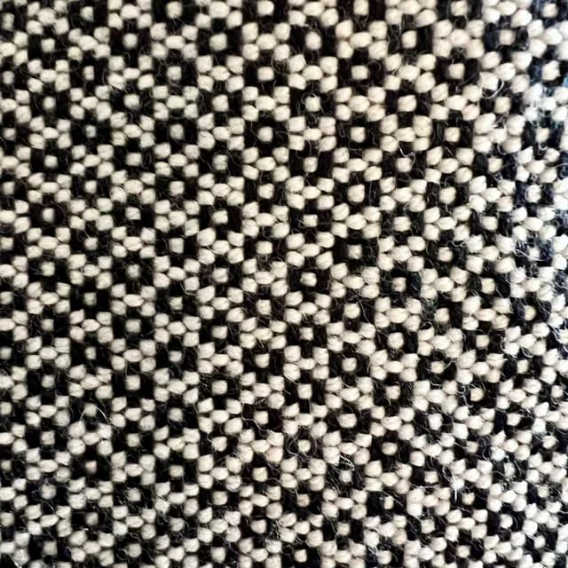 Gros plan sur le motif géométrique et la texture du tissage noir et blanc de l'écharpe.