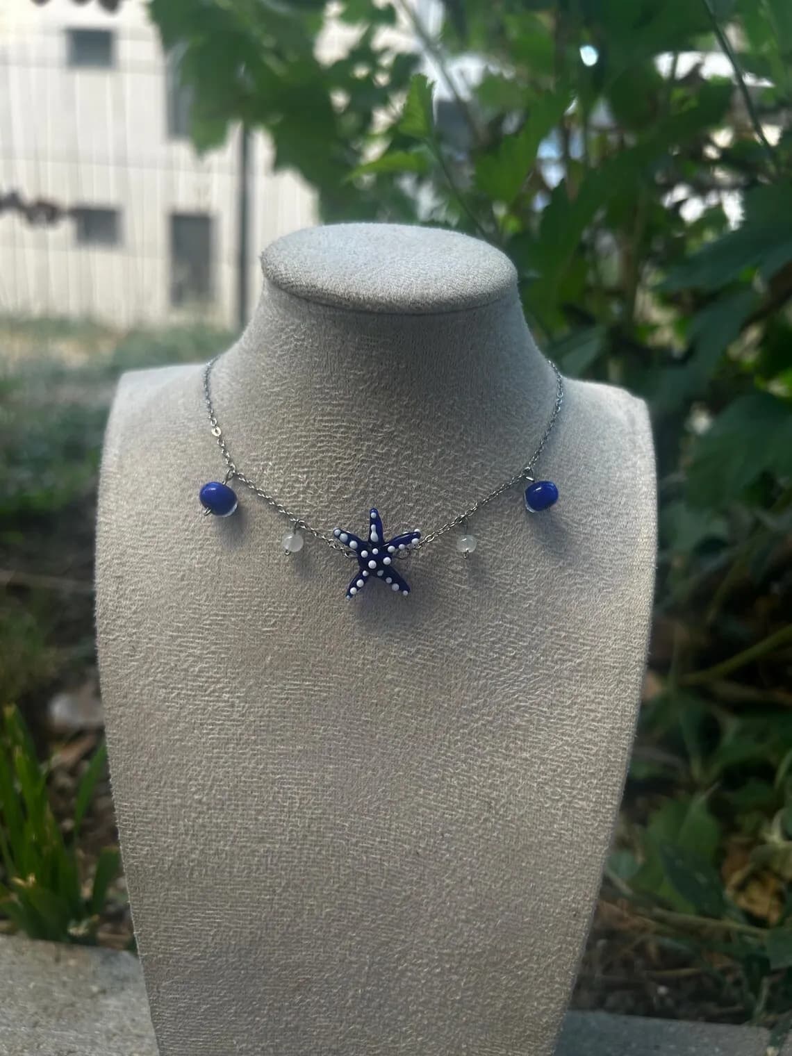 Collier fin avec pendentif étoile de mer bleue et perles porté autour du cou