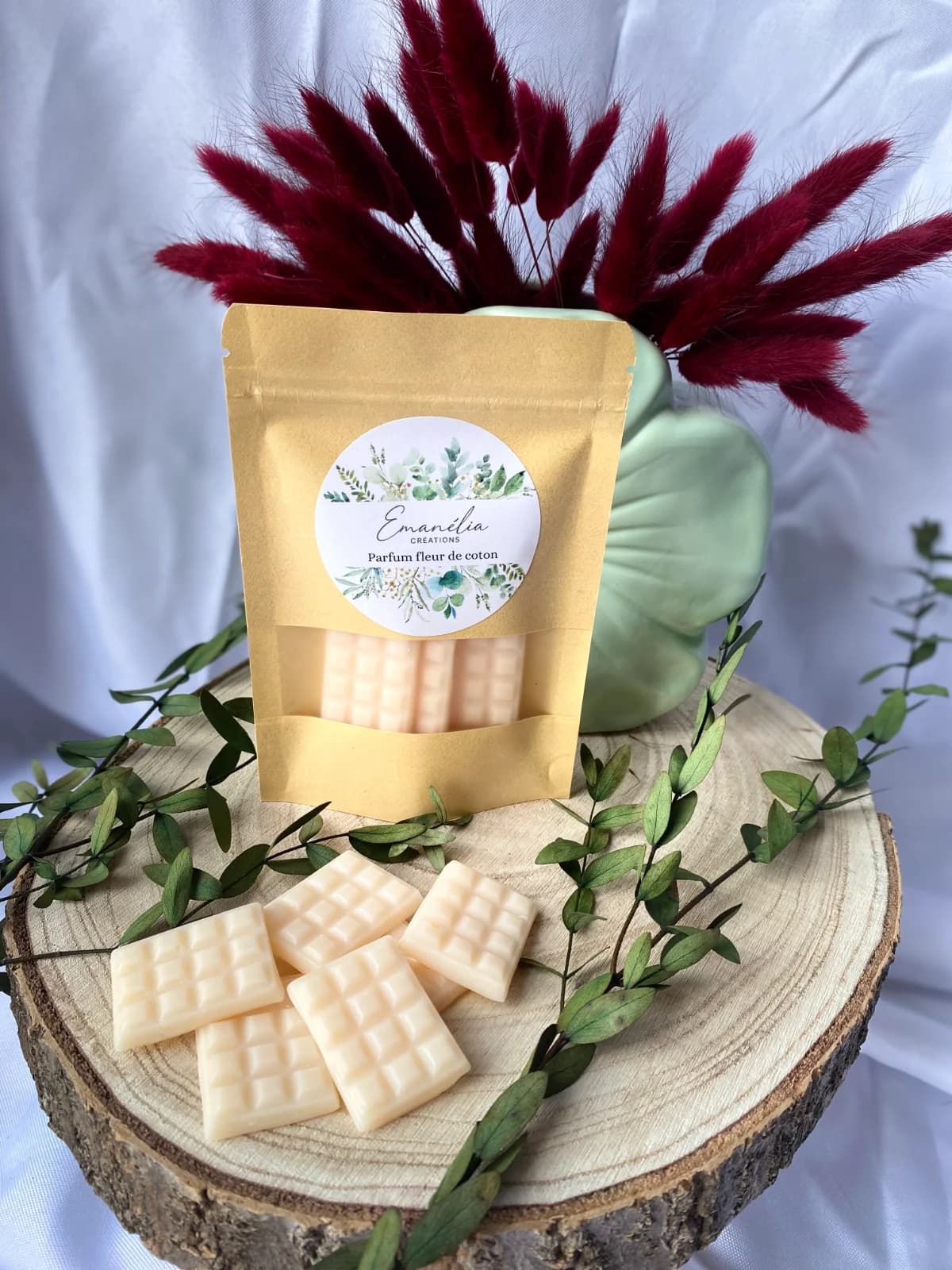 Sachet kraft et fondants parfumés blanc crème en forme de tablettes posés sur un rondin de bois décoré.